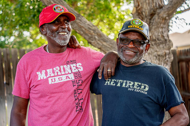 Two Senior African American Military Veterans Embracing Outside in a Backyard Having a Friendly Conversation